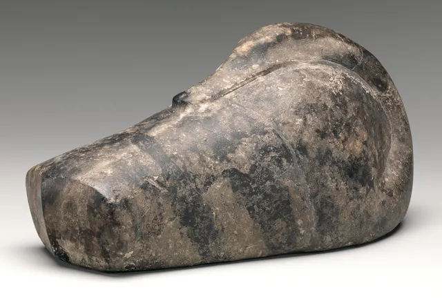 Black stone weight carved as a sleeping duck with its head turned back along its body, from ancient Mesopotamia