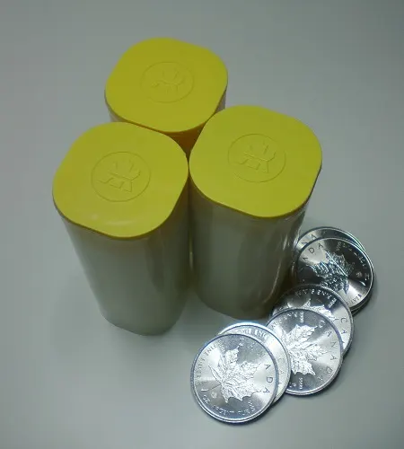Canadian Silver Maple Leaf bullion coins beside three yellow mint tubes