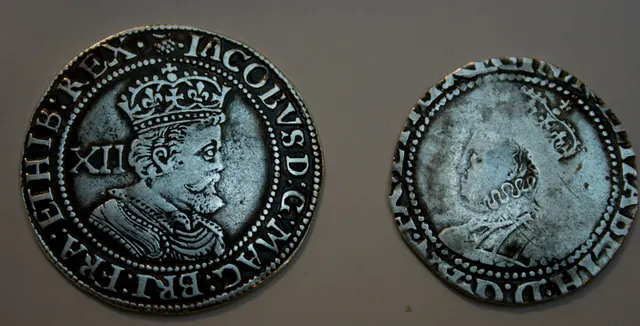 Two English silver shillings side by side: a full James I shilling and a noticeably smaller Elizabeth I shilling with its rim and lettering clipped away