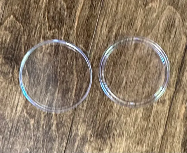 The two clear halves of an open coin capsule lying side by side