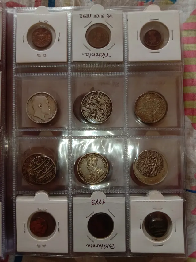 A clear 12-pocket coin page holding old coins, with cardboard 2x2 holders in the top and bottom rows and loose silver coins in the middle