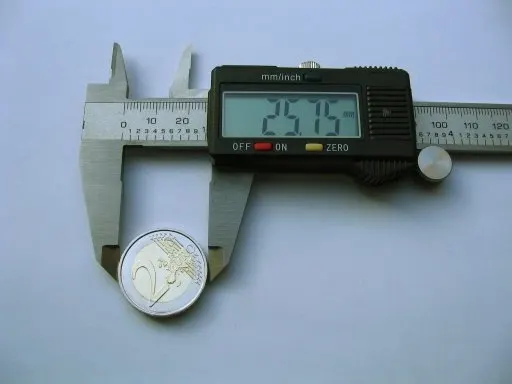 A digital caliper measuring the diameter of a 2 euro coin, with the display reading 25.75 mm