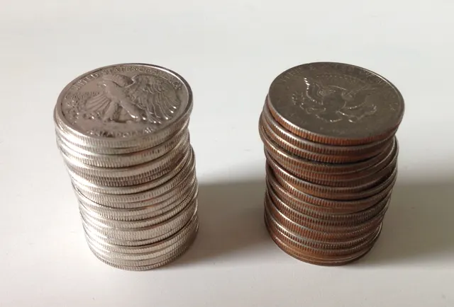 Two stacks of half dollars: solid silver edges next to clad edges with a copper stripe. Dimes and quarters show the same difference