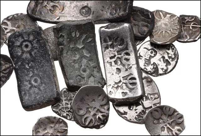 Group of early Indian silver money: short and long Gandharan bent bars beside round and rectangular Mauryan punch-marked coins