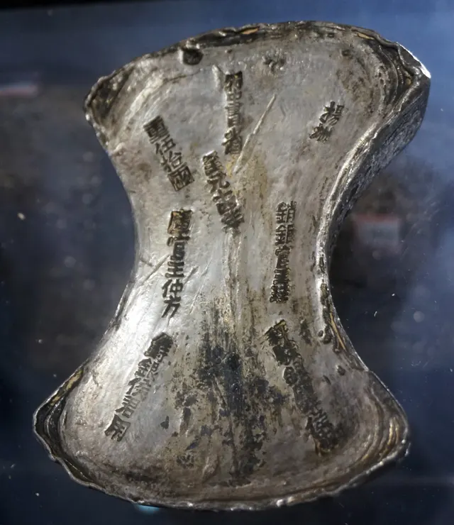 A 50-tael silver ingot cast at Yangzhou in 1277 under the Yuan dynasty, with engraved columns of Chinese characters naming the officials who made and checked it